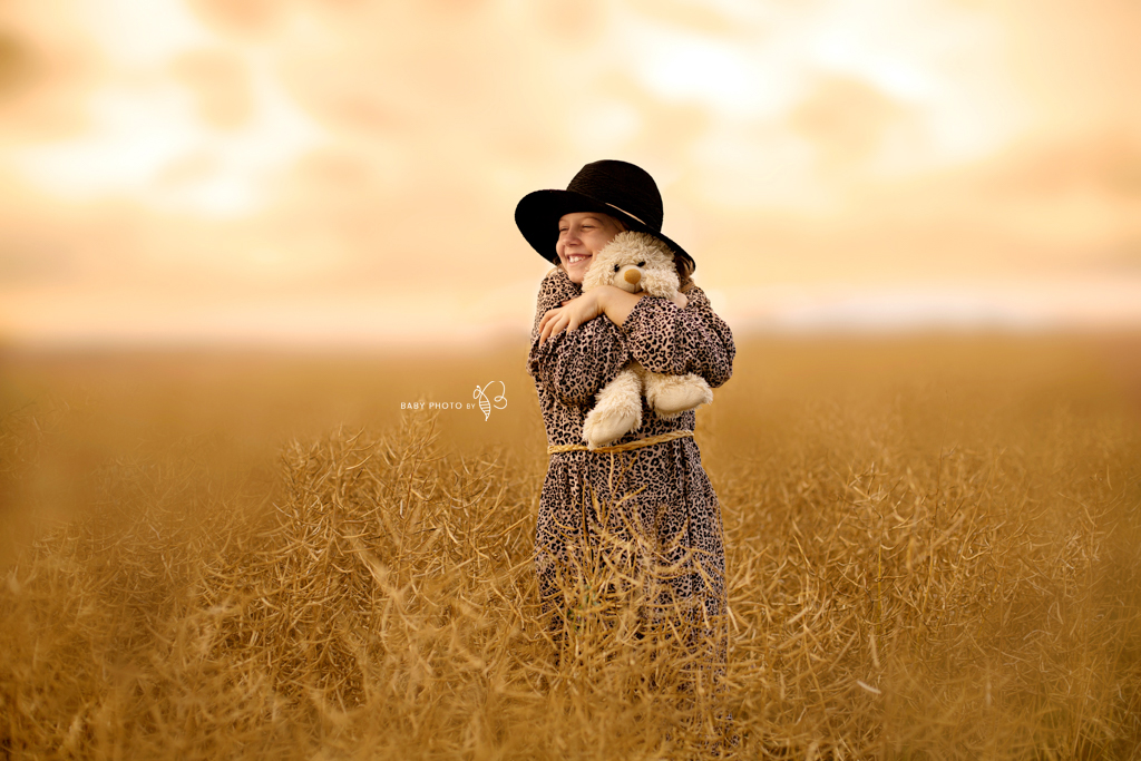 girl with teddy bear in the wheat field
